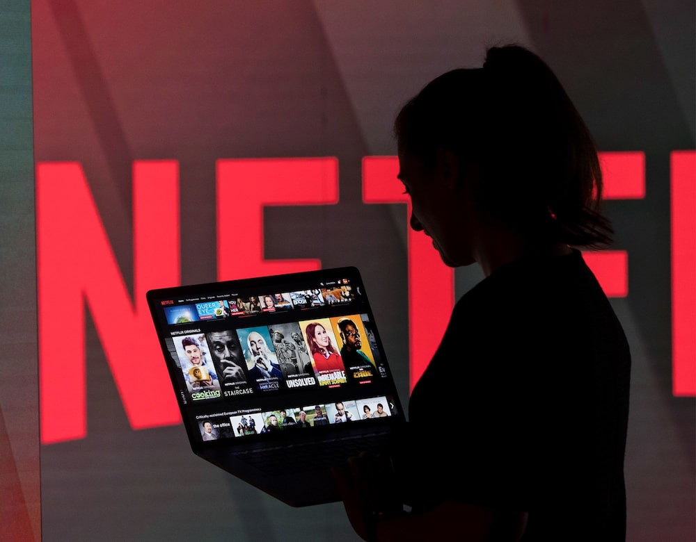 Una mujer navega por la página de inicio de Netflix Inc. en un ordenador portátil, rodeada de pantallas iluminadas que muestran el logotipo de la empresa, en esta fotografía preparada en Londres. Una mujer navega por la página de inicio de Netflix Inc. en un ordenador portátil, rodeada de pantallas iluminadas que muestran el logotipo de la empresa, en esta fotografía preparada en Londres.