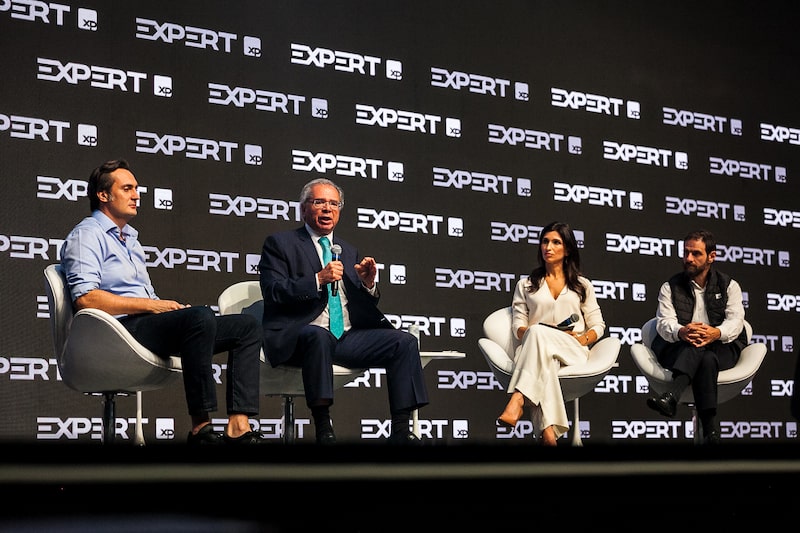 Paulo Guedes durante o evento Expert, ao lado de Rafael Furlanetti (à esq.), diretor institucional, Júlia Leite, analista de política, e Caio Megale, economista-chefe, os três da XP Paulo Guedes durante o evento Expert, ao lado de Rafael Furlanetti (à esq.), diretor institucional, Júlia Leite, analista de política, e Caio Megale, economista-chefe, os três da XP