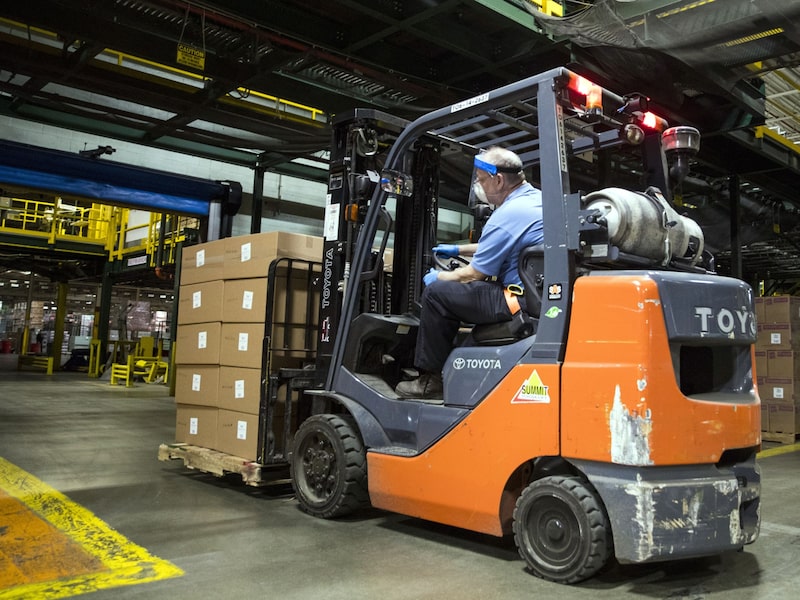 Un trabajador con una mascarilla opera una carretilla elevadora para mover cajas de protectores faciales listos para su envío en la planta de fabricación de Hasbro, propiedad de Cartamundi, en East Longmeadow, Massachusetts, Estados Unidos, el miércoles 29 de abril de 2020. Un trabajador con una mascarilla opera una carretilla elevadora para mover cajas de protectores faciales listos para su envío en la planta de fabricación de Hasbro, propiedad de Cartamundi, en East Longmeadow, Massachusetts, Estados Unidos, el miércoles 29 de abril de 2020.