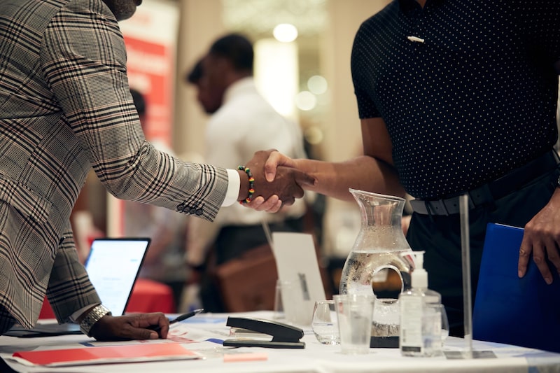 Un solicitante de empleo y un reclutador se dan la mano durante una feria de empleo en Dallas. Fotógrafo: Dylan Hollingsworth/Bloomberg. Un solicitante de empleo y un reclutador se dan la mano durante una feria de empleo en Dallas. Fotógrafo: Dylan Hollingsworth/Bloomberg.