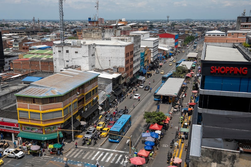 Vista de una concurrida zona comercial, con tráfico, transporte público y vendedores en las calles. Vista de una concurrida zona comercial, con tráfico, transporte público y vendedores en las calles.