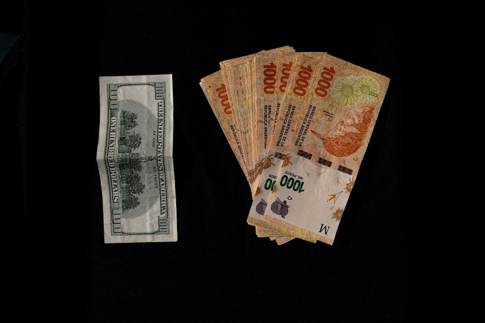 A US hundred dollar banknote and 1000 peso banknotes arranged in Buenos Aires, Argentina, on Thursday, April 27, 2023. Argentina's parallel exchange rate, known as the blue-chip swap, is in free-fall as locals rush to buy the US dollar amid rampant inflation, falling reserves and speculation over a devaluation of the official peso. Photographer: Sarah Pabst/Bloomberg A US hundred dollar banknote and 1000 peso banknotes arranged in Buenos Aires, Argentina, on Thursday, April 27, 2023. Argentina's parallel exchange rate, known as the blue-chip swap, is in free-fall as locals rush to buy the US dollar amid rampant inflation, falling reserves and speculation over a devaluation of the official peso. Photographer: Sarah Pabst/Bloomberg