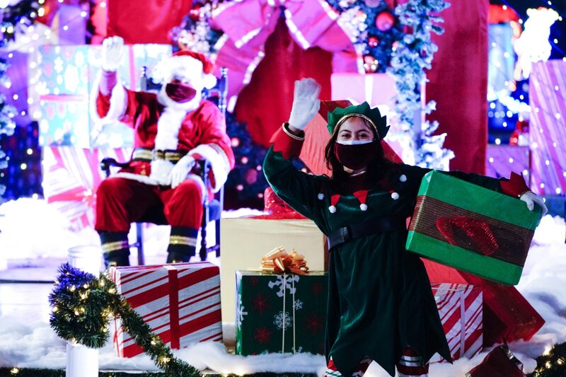 Performers dressed as Santa Claus and an elf wear protective masks while waving during the Night of Lights OC drive-thru Christmas light show at the OC Fair & Event Center in Costa Mesa, California, U.S., on Saturday, Dec. 12, 2020. California's average rate of positive tests over 14 days reached 8.8%, the highest since the spring as cases surged to another record. Photographer: Bing Guan/Bloomberg Performers dressed as Santa Claus and an elf wear protective masks while waving during the Night of Lights OC drive-thru Christmas light show at the OC Fair & Event Center in Costa Mesa, California, U.S., on Saturday, Dec. 12, 2020. California's average rate of positive tests over 14 days reached 8.8%, the highest since the spring as cases surged to another record. Photographer: Bing Guan/Bloomberg