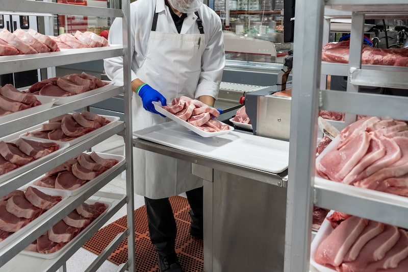 Un trabajador empaca cortes de carne en una planta procesadora. Un trabajador empaca cortes de carne en una planta procesadora.