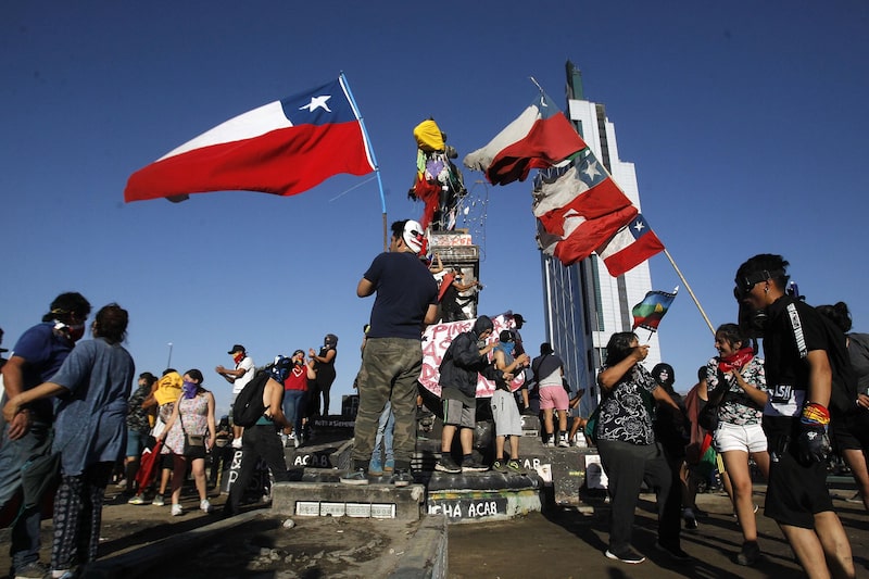 Los manifestantes ondean banderas chilenas durante las protestas contra el gobierno del presidente Sebastián Piñera en la Plaza Italia, el 1 de diciembre de 2019, en Santiago. Los manifestantes ondean banderas chilenas durante las protestas contra el gobierno del presidente Sebastián Piñera en la Plaza Italia, el 1 de diciembre de 2019, en Santiago.