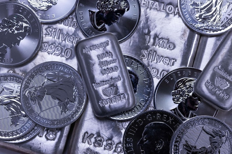 Una selección de lingotes de plata y monedas de plata de una onza. Una selección de lingotes de plata y monedas de plata de una onza.