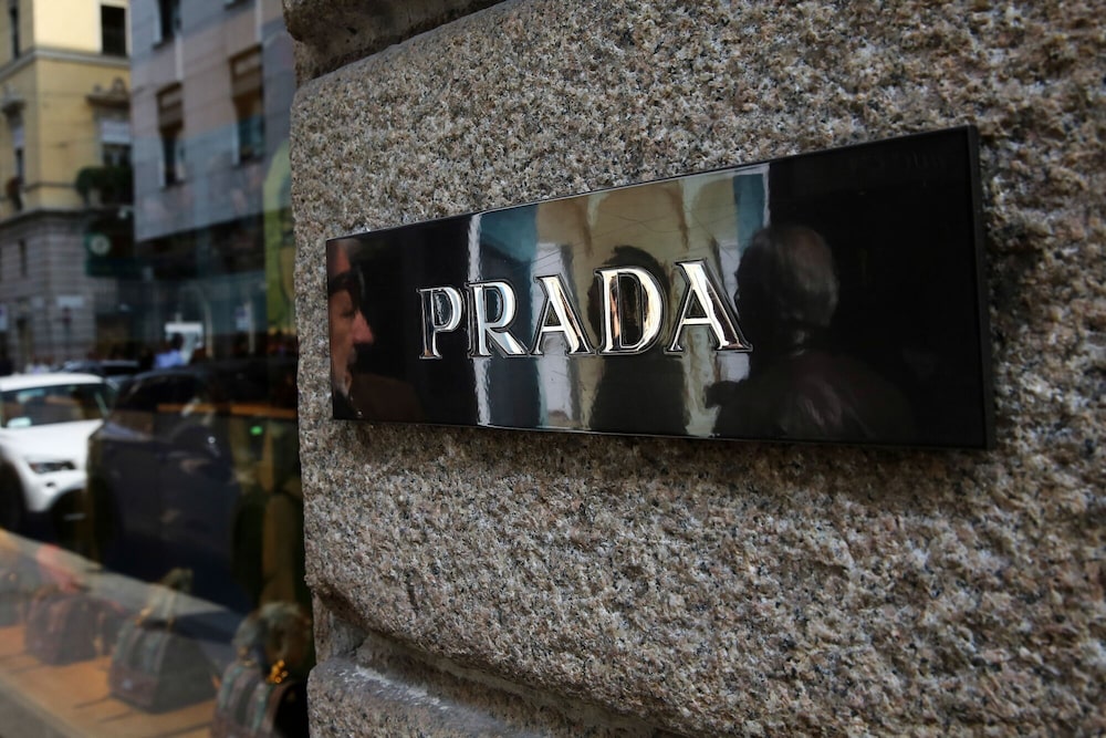 Un cartel de Prada SpA se encuentra en la entrada de una de sus tiendas en el centro de Milán, Italia. Un cartel de Prada SpA se encuentra en la entrada de una de sus tiendas en el centro de Milán, Italia.