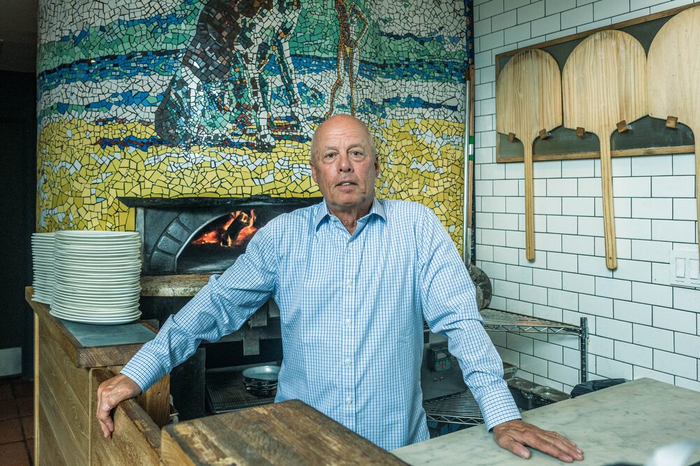 Homem calvo em vestes de cor clara em um restaurante de forno a lenha Homem calvo em vestes de cor clara em um restaurante de forno a lenha