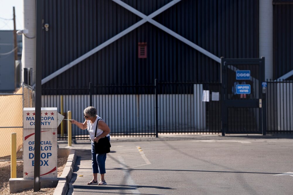 Uma eleitora entrega uma cédula de votação em uma urna dentro de um estacionamento em Phoenix (Foto: Rebecca Noble/Bloomberg) Uma eleitora entrega uma cédula de votação em uma urna dentro de um estacionamento em Phoenix (Foto: Rebecca Noble/Bloomberg)