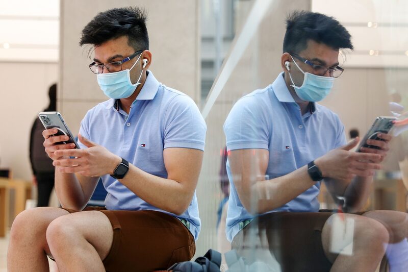 Una persona con mascarilla usa un iPhone Una persona con mascarilla usa un iPhone