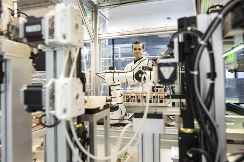 Em primeiro plano, um equipamento de laboratório, em segundo plano, ao centro da foto, um homem Em primeiro plano, um equipamento de laboratório, em segundo plano, ao centro da foto, um homem