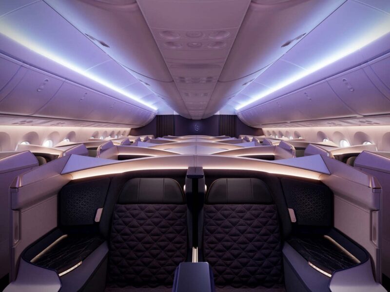 A cabine inclui painéis de privacidade, assentos reclináveis, iluminação ambiente, telas grandes e Wi-Fi de alta velocidade, tudo envolto em uma paleta de cores de roxos profundos, dourado e pedra A cabine inclui painéis de privacidade, assentos reclináveis, iluminação ambiente, telas grandes e Wi-Fi de alta velocidade, tudo envolto em uma paleta de cores de roxos profundos, dourado e pedra