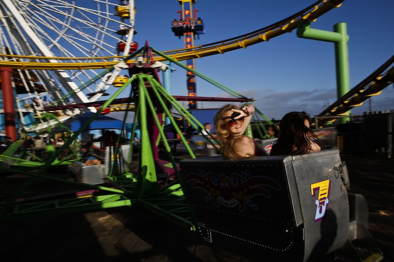 Tourists Tea Wagner, 16, left, of Austria and Jexi Keith, 16, of Costa Rica ride the Pacific Park Scrambler near the Ferris wheel on the Santa Monica Pier in Santa Monica, California, U.S., on Monday, Aug. 5, 2013. Overall U.S. tourism-related sales increased 6.8% in the second quarter of 2013 as compared to 2012. Photographer: Patrick Fallon/Bloomberg *** Local Caption *** Tea Wagner; Jexi Keith Tourists Tea Wagner, 16, left, of Austria and Jexi Keith, 16, of Costa Rica ride the Pacific Park Scrambler near the Ferris wheel on the Santa Monica Pier in Santa Monica, California, U.S., on Monday, Aug. 5, 2013. Overall U.S. tourism-related sales increased 6.8% in the second quarter of 2013 as compared to 2012. Photographer: Patrick Fallon/Bloomberg *** Local Caption *** Tea Wagner; Jexi Keith
