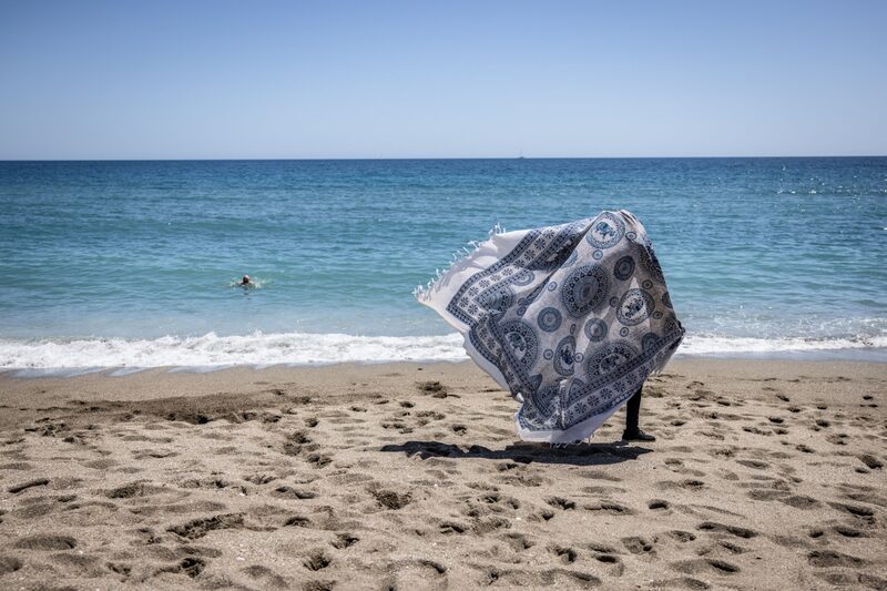 Un vendedor lleva telas a la venta en la playa de la Malagueta de Málaga, España. Un vendedor lleva telas a la venta en la playa de la Malagueta de Málaga, España.