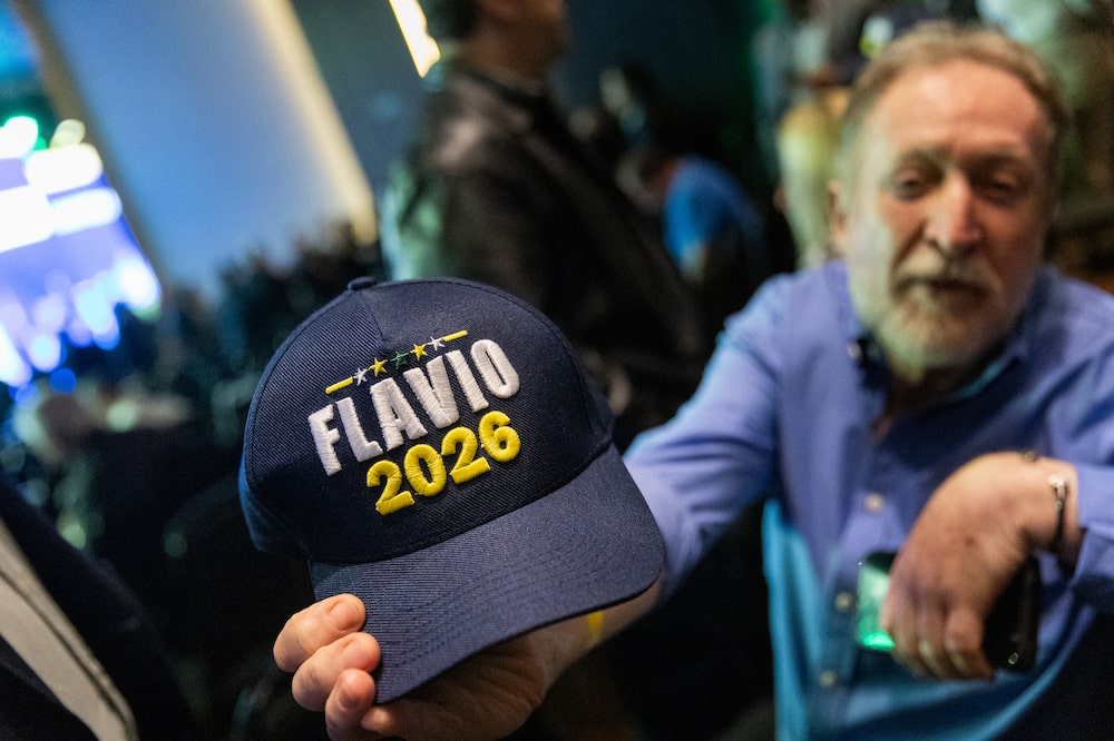 An attendee holds a "Flavio 2026" hat during the Great Association Gathering in Sao Paulo, Brazil, on Tuesday, Oct. 13, 2026. Flavio Bolsonaro leads incumbent Luiz Inacio Lula da Silva ahead of Brazil's presidential runoff, a new poll showed, building on momentum after a surprise showing in the first round vote. Photographer: Tuane Fernandes/Bloomberg An attendee holds a "Flavio 2026" hat during the Great Association Gathering in Sao Paulo, Brazil, on Tuesday, Oct. 13, 2026. Flavio Bolsonaro leads incumbent Luiz Inacio Lula da Silva ahead of Brazil's presidential runoff, a new poll showed, building on momentum after a surprise showing in the first round vote. Photographer: Tuane Fernandes/Bloomberg