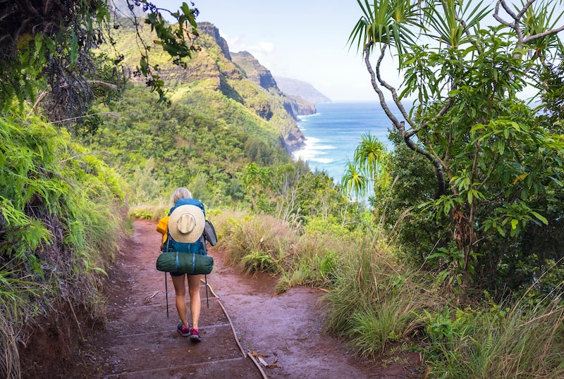 Una mujer joven haciendo mochilerismo en el sendero Kalalau de la costa Napali en Kauai, Hawái. Una mujer joven haciendo mochilerismo en el sendero Kalalau de la costa Napali en Kauai, Hawái.