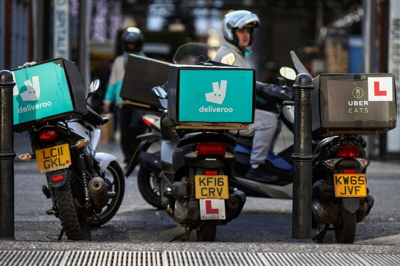 Motocicletas de Deliveroo, operada por Roofoods Ltd. junto a una moto de UberEats, operada por Uber Technologies Inc. mientras sus conductores esperan pedidos de comida. Motocicletas de Deliveroo, operada por Roofoods Ltd. junto a una moto de UberEats, operada por Uber Technologies Inc. mientras sus conductores esperan pedidos de comida.