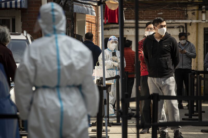 Trabajadores con equipos de protección personal vigilan mientras los residentes participan en una ronda de pruebas de Covid-19 durante un cierre en Shanghái, el 18 de abril. Trabajadores con equipos de protección personal vigilan mientras los residentes participan en una ronda de pruebas de Covid-19 durante un cierre en Shanghái, el 18 de abril.