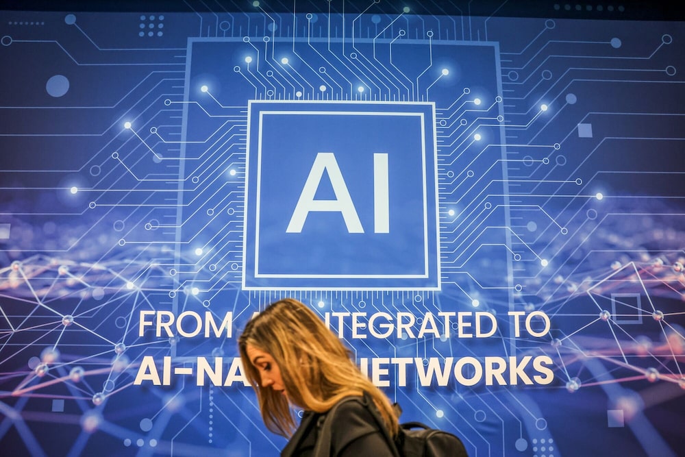 Una mujer pasa frente a una pantalla con una ilustración alusiva a la inteligencia artificial y las redes tecnológicas. Una mujer pasa frente a una pantalla con una ilustración alusiva a la inteligencia artificial y las redes tecnológicas.