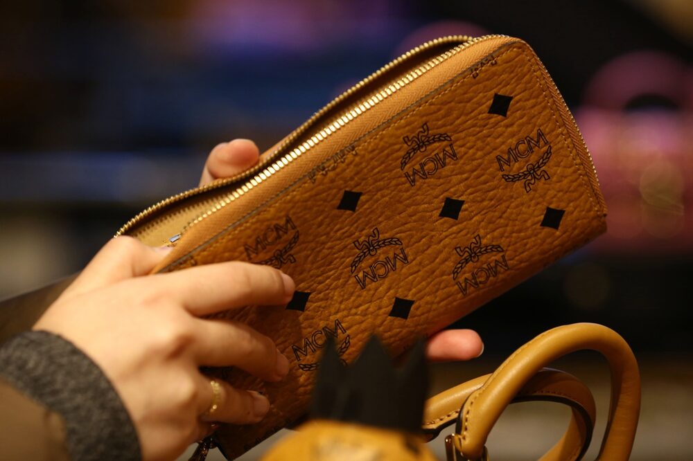 Un cliente inspecciona una cartera dentro de una tienda. Un cliente inspecciona una cartera dentro de una tienda.