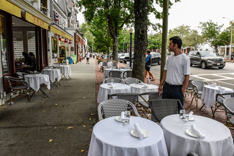 Mesas com toalhas brancas em uma calçada arborizada Mesas com toalhas brancas em uma calçada arborizada