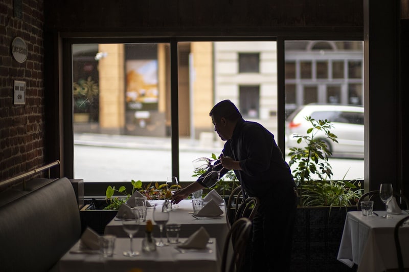 Un mesero prepara una mesa en un restaurante en San Francisco, California, EE.UU. Un mesero prepara una mesa en un restaurante en San Francisco, California, EE.UU.
