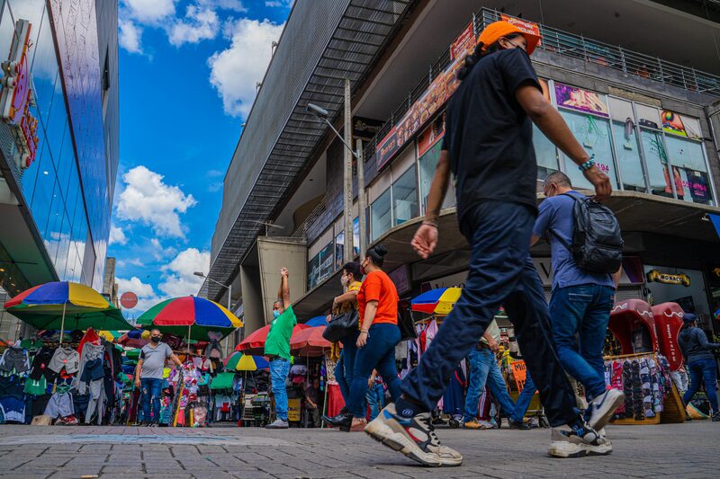 Pedestrians wearing protective masks walk past street vendors in Medellin, Colombia, on Thursday, May 20, 2021. Colombia's dollar bonds dropped and the peso led losses among emerging-market currencies after S&P Global Ratings cut the countrys credit rating to junk amid a political crisis and mass unrest. Photographer: Edinson Arroyo/Bloomberg Pedestrians wearing protective masks walk past street vendors in Medellin, Colombia, on Thursday, May 20, 2021. Colombia's dollar bonds dropped and the peso led losses among emerging-market currencies after S&P Global Ratings cut the countrys credit rating to junk amid a political crisis and mass unrest. Photographer: Edinson Arroyo/Bloomberg