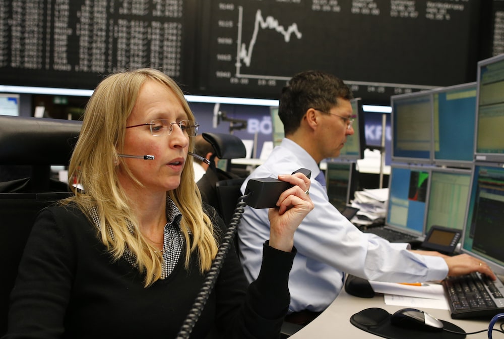 A financial trader uses a telephone as she works at her desk against the background of the DAX Index curve at the Frankfurt Stock Exchange in Frankfurt, Germany, on Monday, March 17, 2014. European stocks advanced, following their biggest weekly drop since January, as companies from RWE AG to Vodafone Group Plc rose amid renewed merger-and-acquisition activity. Photographer: Ralph Orlowski/Bloomberg A financial trader uses a telephone as she works at her desk against the background of the DAX Index curve at the Frankfurt Stock Exchange in Frankfurt, Germany, on Monday, March 17, 2014. European stocks advanced, following their biggest weekly drop since January, as companies from RWE AG to Vodafone Group Plc rose amid renewed merger-and-acquisition activity. Photographer: Ralph Orlowski/Bloomberg