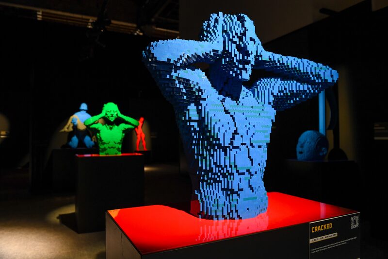 Escultura feita de blocos de montar azuis. A escultura representa um torso humano exibindo sinais de desespero com as mãos na cabeça Escultura feita de blocos de montar azuis. A escultura representa um torso humano exibindo sinais de desespero com as mãos na cabeça