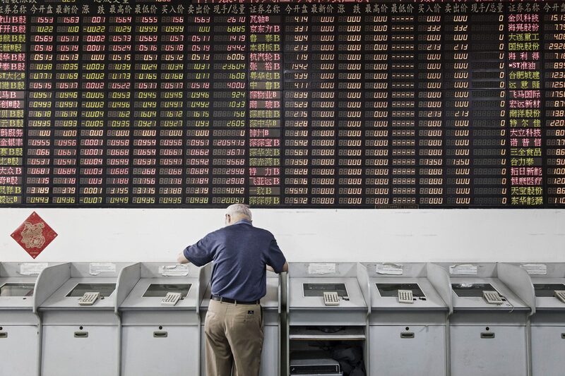 Um investidor está em um terminal de negociação em frente a um quadro eletrônico de ações em uma corretora de valores mobiliários em Xangai, China Um investidor está em um terminal de negociação em frente a um quadro eletrônico de ações em uma corretora de valores mobiliários em Xangai, China