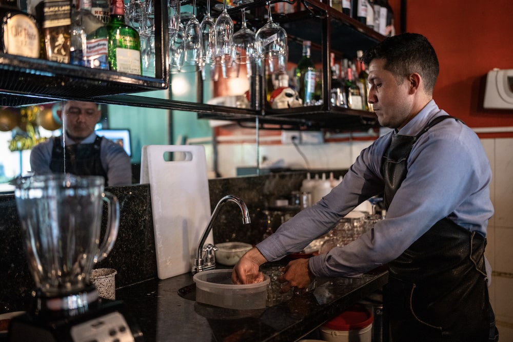 David Carima lava vasos con agua recogida en un balde en Casa Frida, un restaurante en el barrio de la Macarena, Bogotá, Colombia el 24 de mayo. David Carima lava vasos con agua recogida en un balde en Casa Frida, un restaurante en el barrio de la Macarena, Bogotá, Colombia el 24 de mayo.