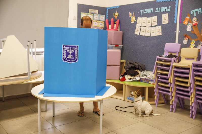 Un votante se prepara para emitir su voto mientras un perro espera al lado en un colegio electoral en Tel Aviv, Israel, el martes 23 de marzo de 2021. Un votante se prepara para emitir su voto mientras un perro espera al lado en un colegio electoral en Tel Aviv, Israel, el martes 23 de marzo de 2021.