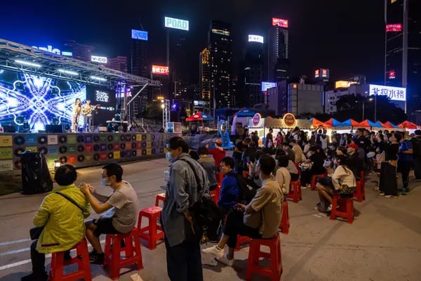 Visitantes escuchan una actuación musical en un mercado nocturno de Hong Kong, China.