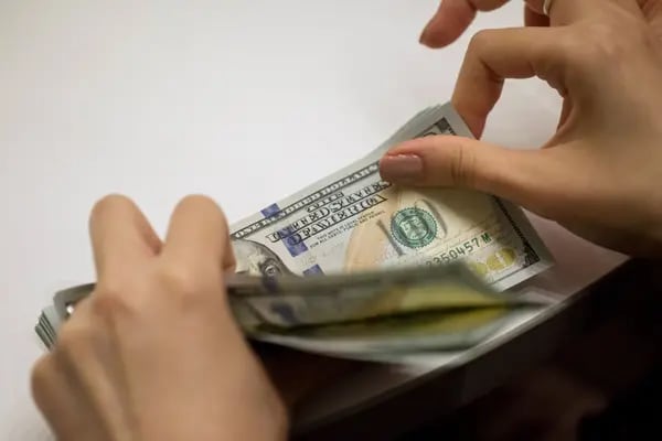Un empleado cuenta una pila de billetes de 100 dólares estadounidenses.