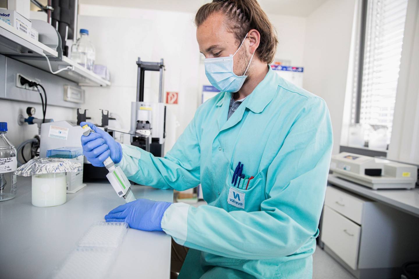 Un técnico de laboratorio con mascarilla protectora utiliza un gotero de pipeta multicanal, durante el proceso de cuantificación del antígeno en la investigación de la vacuna contra el coronavirus en los laboratorios Valneva de Viena.