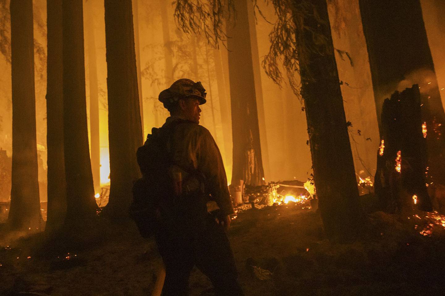 Un bombero de la estación de CDF de Jameson Creek lucha contra un incendio en una propiedad en Acorn Drive durante el incendio del complejo CZU Lightning en el condado de Santa Cruz, California.