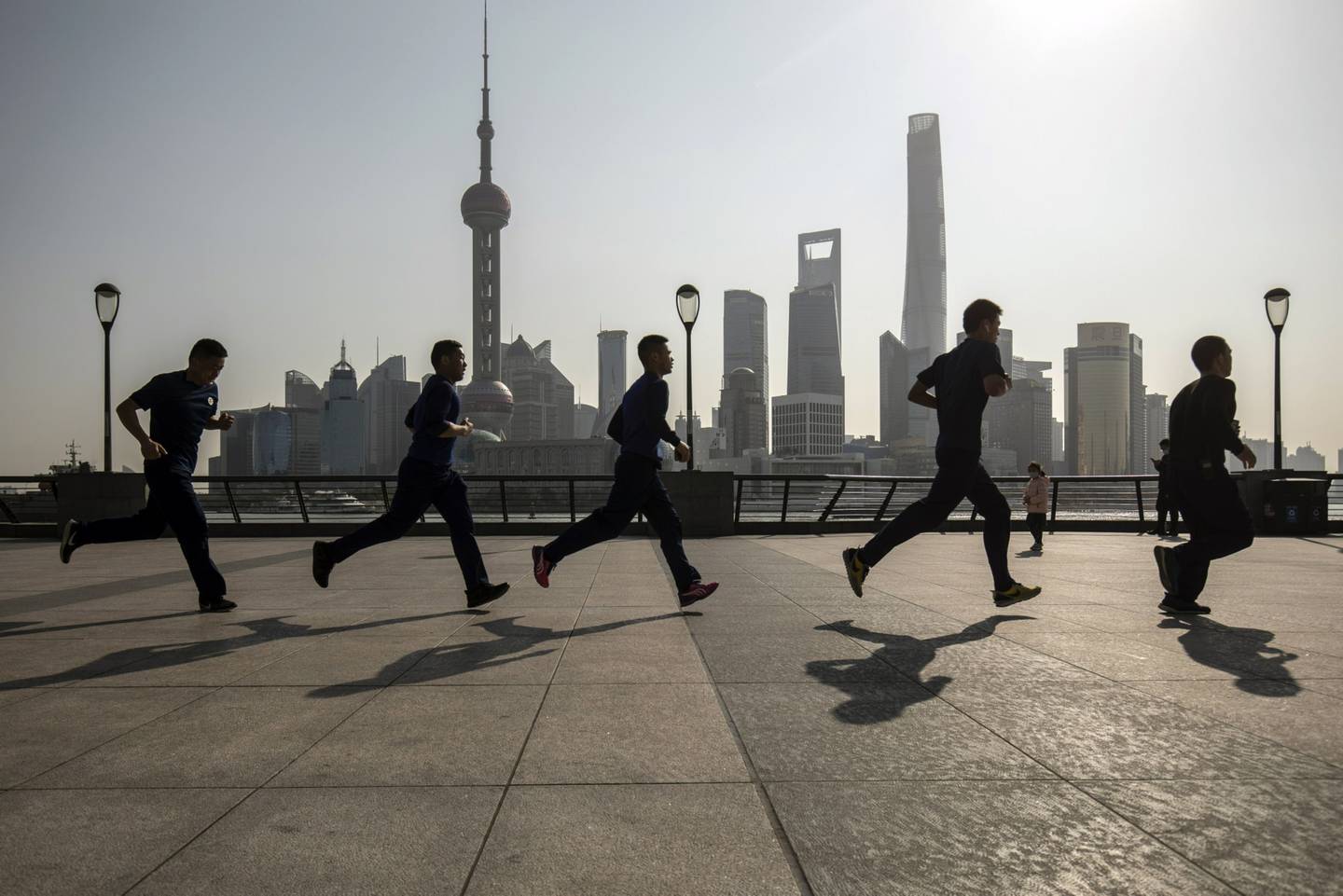 Los corredores corren a lo largo del Bund frente a los edificios del distrito financiero de Lujiazui, al otro lado del río Huangpu, en Shanghai, China, el viernes 27 de febrero de 2022. Fotógrafo: Qilai Shen/Bloomberg