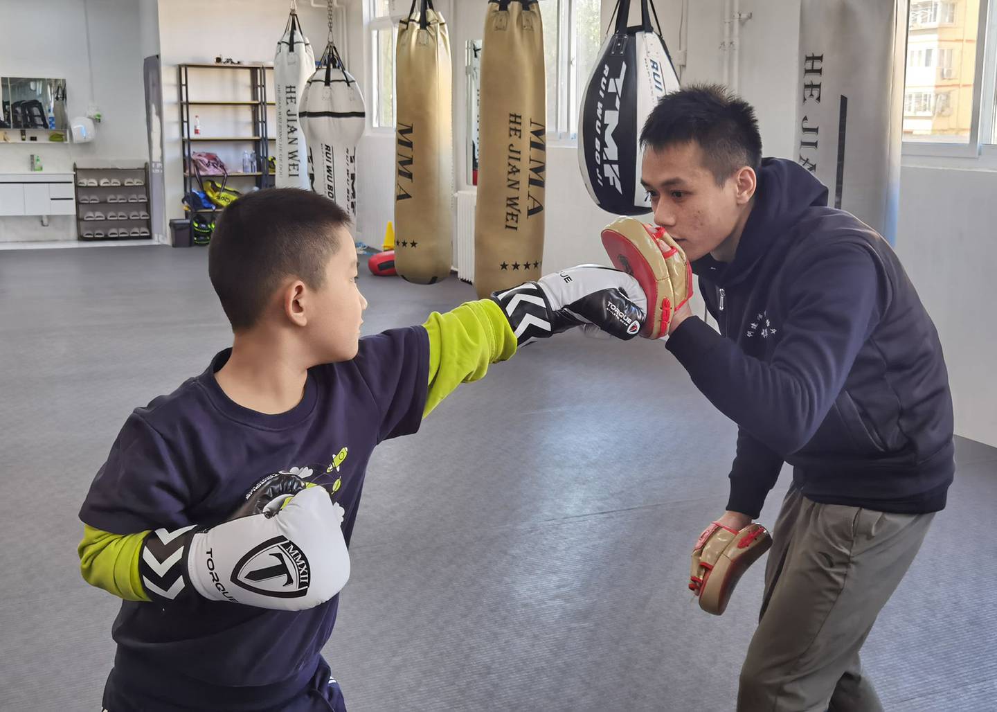 Guoguo, left, trains with He Jianwei at a boxing club in east Beijing.