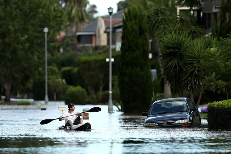 Un hombre pasa junto a un automóvil en una calle sumergida en las aguas de la inundación en el suburbio de McGraths Hill en Sydney, Australia, el miércoles 24 de marzo de 2021.dfd