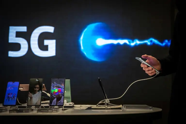 Un cliente navega por un teléfono inteligente frente a un logotipo de 5G dentro del centro Movistar, operado por Telefónica SA, en Barcelona, ​​España, el jueves 21 de enero de 2021.dfd
