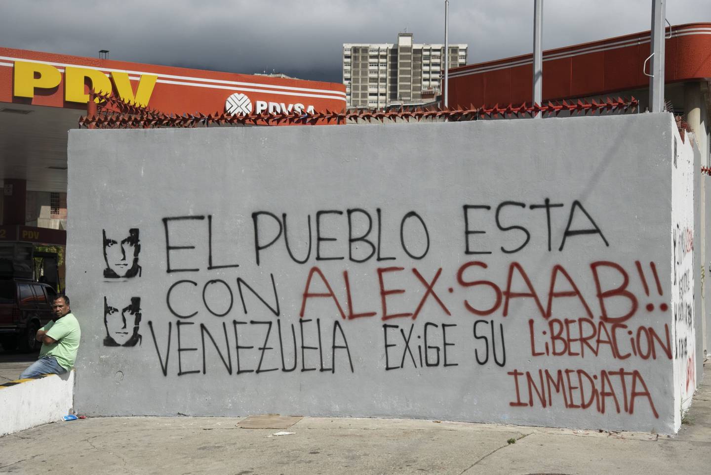 Una persona sentada junto a una pared con un grafiti que dice: "¡El pueblo está con Alex Saab! Venezuela exige su liberación inmediata", en Caracas, Venezuela, el jueves 4 de febrero de 2021.dfd