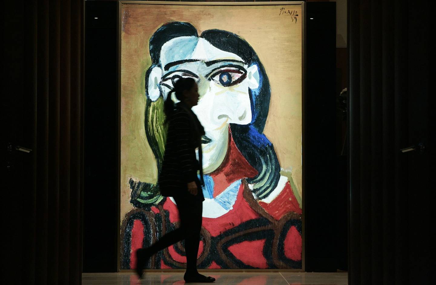Un visitante pasa junto a un cartel de la obra del artista Pablo Picasso titulada "Jeune fille aux cheveux noirs (Dora Maar)" en una exposición de Sotheby's en Hong Kong, China.dfd