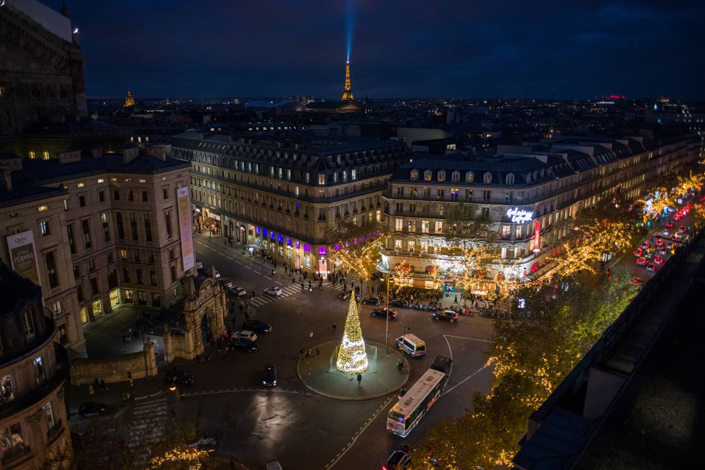 Shoppers pass a giant illuminated Christmas tree viewed from the Galeries Lafayette department store in Paris, France, on Wednesday, Nov. 24. Photographer: Nathan Laine/Bloombergdfd