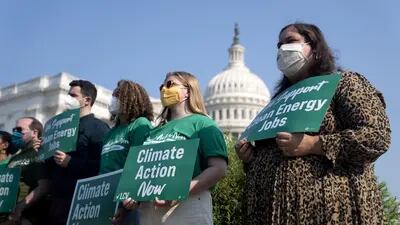 Los activistas sostienen carteles de "Acción climática ahora" durante una conferencia de prensa fuera del Capitolio de EE.UU., en Washington.