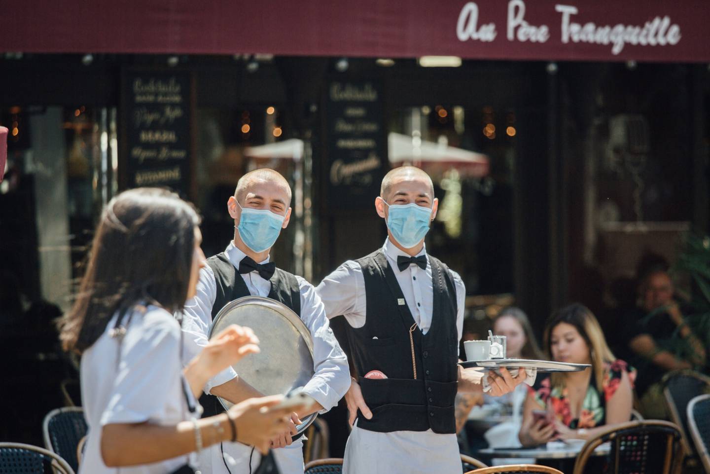 Meseros utilizan mascarillas mientras esperan a los clientes en la terraza de un restaurante mientras Francia reabre cafés, restaurantes y espacios públicos, en París, Francia, el martes 2 de junio de 2020.