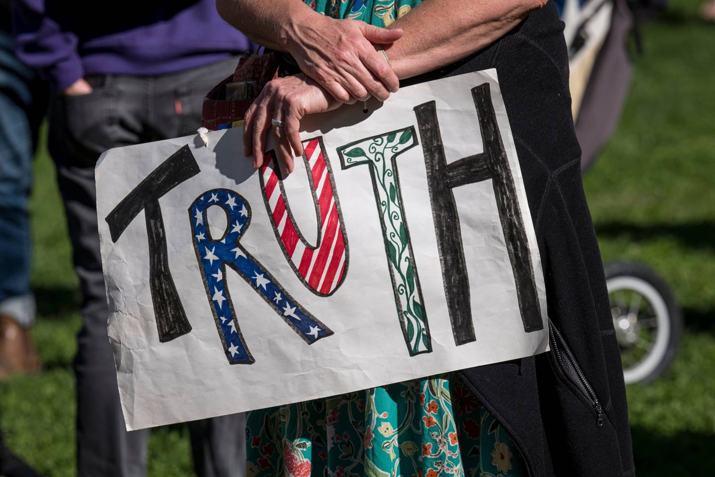 A demonstrator holds a sign reading "Truth" at a protest.