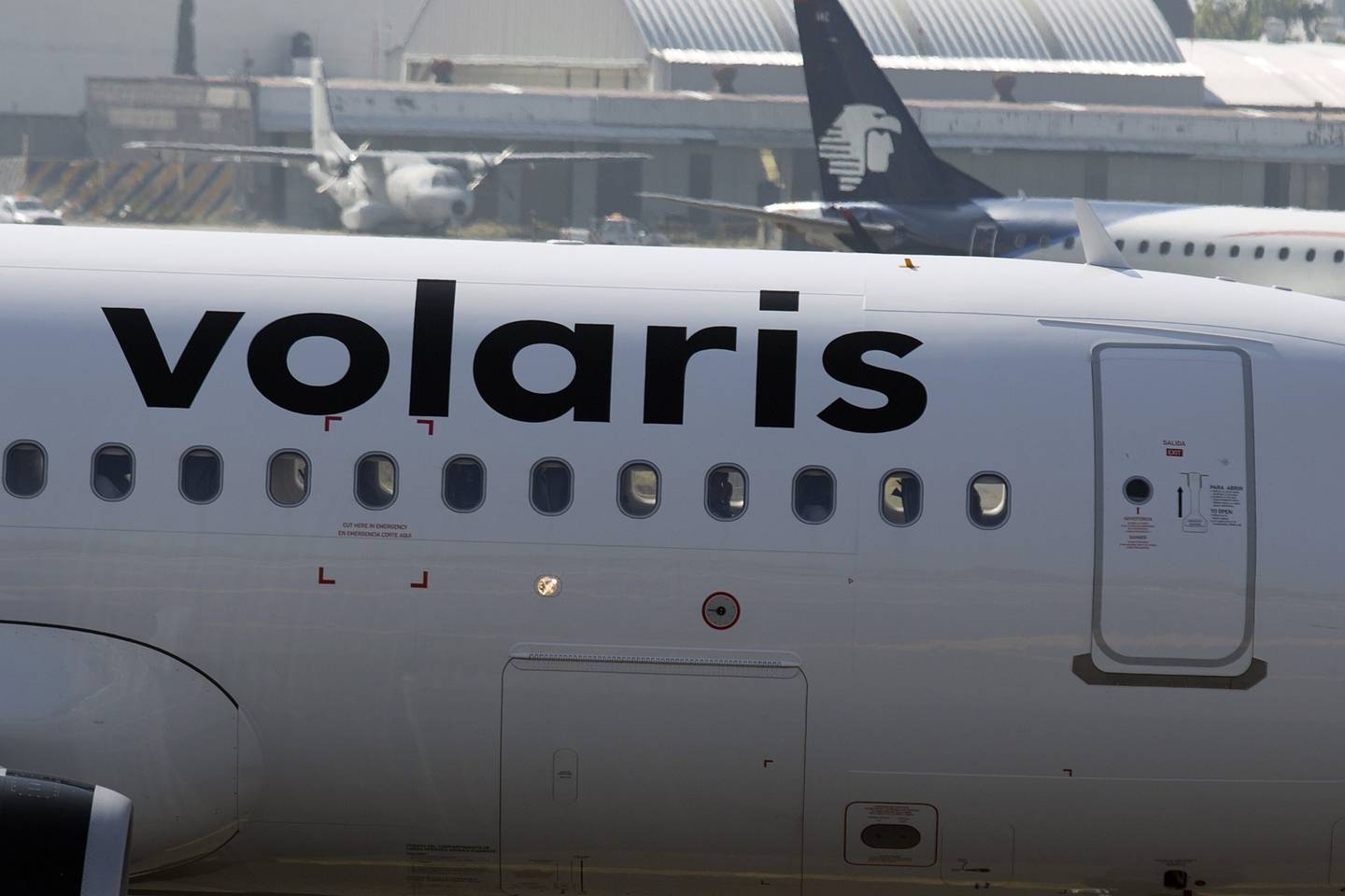 The tail section of a Grupo Aeromexico SAB jet is seen behind a Volaris plane at Benito Juarez International Airport in Mexico City, Mexico, on Tuesday, Sept. 17, 2013. Volaris, the low-cost Mexican airline backed by U.S. private-equity firm Indigo Partners LLC, is touting market-share growth to potential investors in its initial share sale as the value of its public peer languishes. Photographer: Susana Gonzalez/Bloomberg