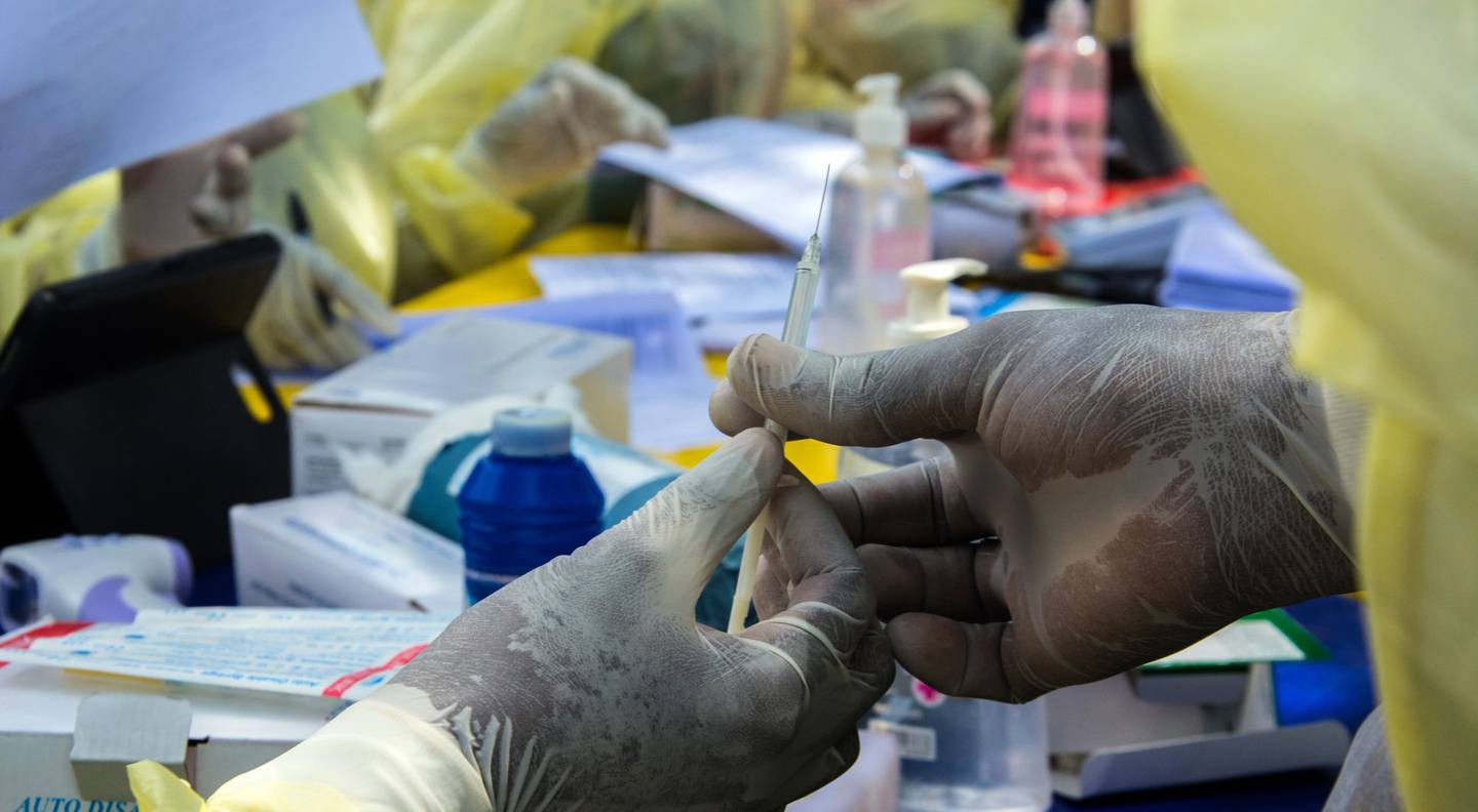 Un trabajador sanitario del Ministerio de Salud de Guinea entrega una jeringa con una vacuna contra el ébola a su colega en Gueckedou, Guinea, el 23 de febrero de 2021.