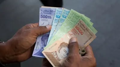 Una persona sostiene un nuevo billete de 500.000 bolívares junto a los antiguos billetes de 10.000, 20.000 y 50.000 bolívares frente a un banco en Caracas, Venezuela, el lunes 15 de marzo de 2021.