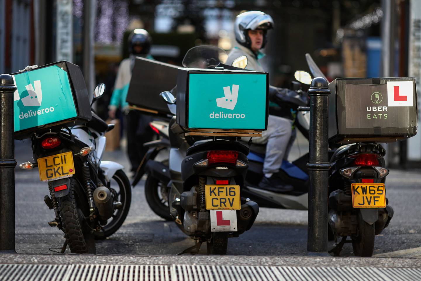 Motocicletas de Deliveroo, operada por Roofoods Ltd. junto a una moto de UberEats, operada por Uber Technologies Inc. mientras sus conductores esperan pedidos de comida.